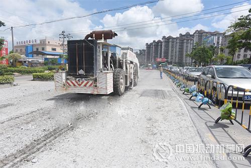  一輛大型共振破碎機行駛過后，路面留下一行共振破碎的水泥碎石