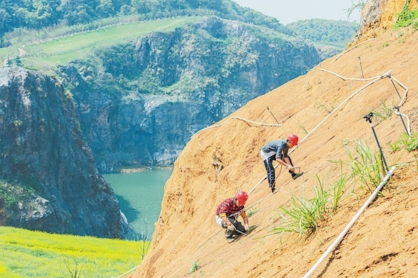 3月28日，武漢市江夏區(qū)靈山生態(tài)文化旅游區(qū)“礦花苑”景區(qū)一期，施工人員在覆土的山體上種植樹種。